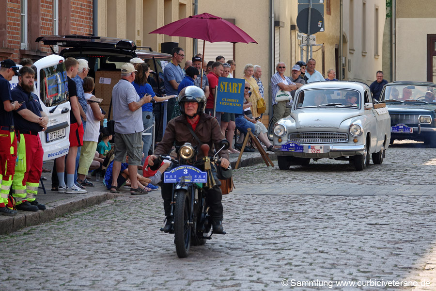 Bild: Start zur Sonntagsausfahrt vor dem Rathaus in Zörbig. Teilnehmer und Fahrzeuge werden von Fahrtleiter Ralf Zschoche und seiner Tochter Anne kurz vorgestellt.