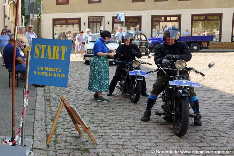 Bild: Start zur Sonntagsausfahrt vor dem Rathaus in Zörbig. Teilnehmer und Fahrzeuge werden von Fahrtleiter Ralf Zschoche und seiner Tochter Anne kurz vorgestellt.